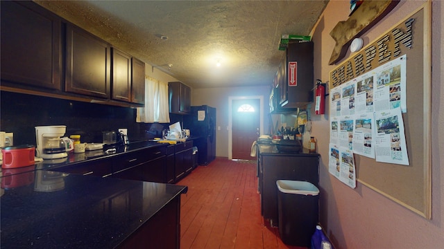 kitchen with dark brown cabinets, a textured ceiling, fridge, and hardwood / wood-style floors