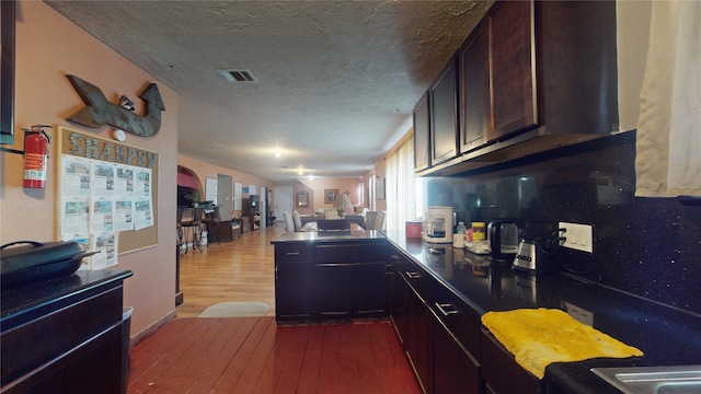 kitchen with dark brown cabinetry, hardwood / wood-style floors, and a textured ceiling