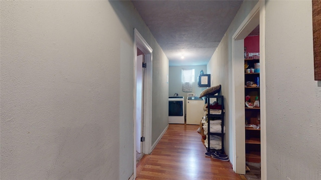 hall with hardwood / wood-style flooring, washing machine and dryer, and a textured ceiling