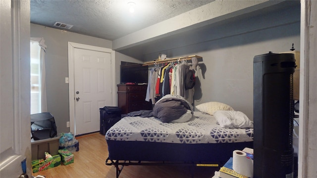 bedroom featuring hardwood / wood-style floors, a closet, and a textured ceiling