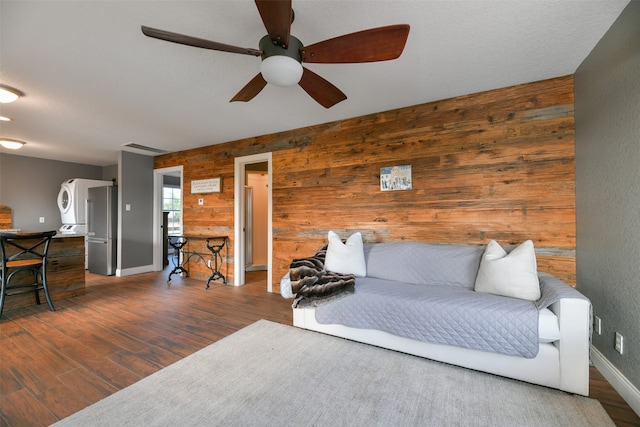 living room with dark hardwood / wood-style floors, ceiling fan, and wood walls