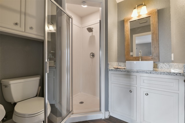 bathroom with hardwood / wood-style floors, an enclosed shower, vanity, and toilet