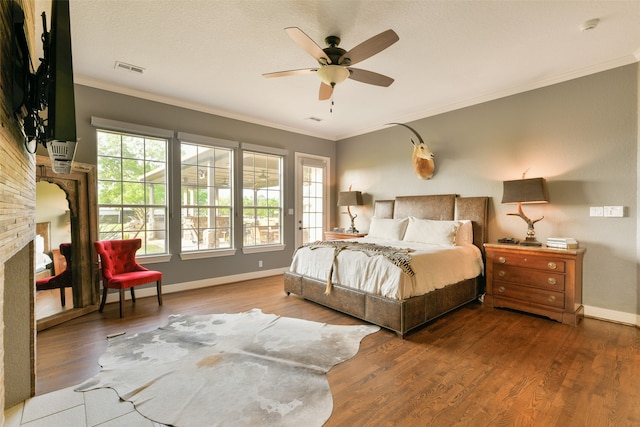 bedroom featuring hardwood / wood-style floors, ornamental molding, ceiling fan, and a fireplace