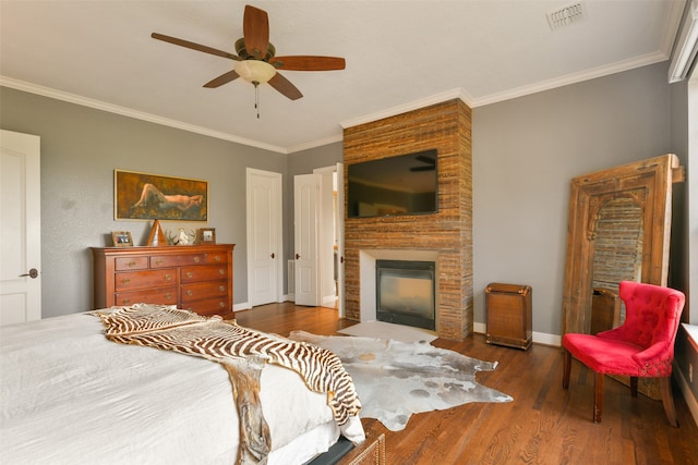 bedroom with a multi sided fireplace, ornamental molding, ceiling fan, and dark hardwood / wood-style floors