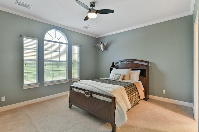 carpeted bedroom with ornamental molding and ceiling fan