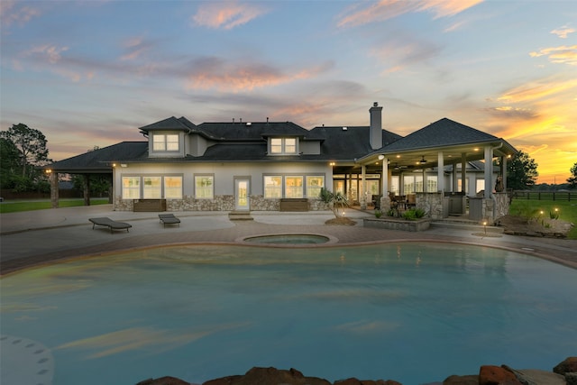 pool at dusk featuring a patio area, an in ground hot tub, and ceiling fan