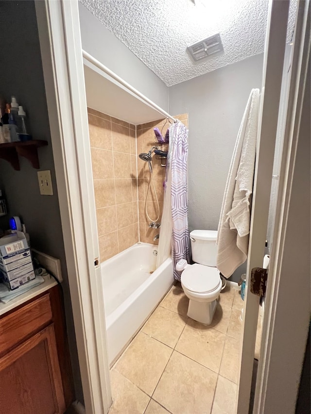 bathroom featuring a textured ceiling, shower / bath combination with curtain, toilet, and tile floors