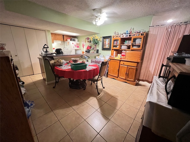 tiled dining area featuring a textured ceiling and ceiling fan