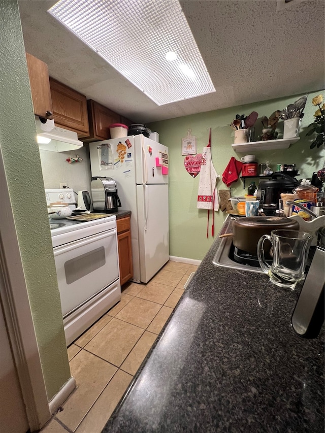 kitchen featuring a textured ceiling, white appliances, and light tile floors