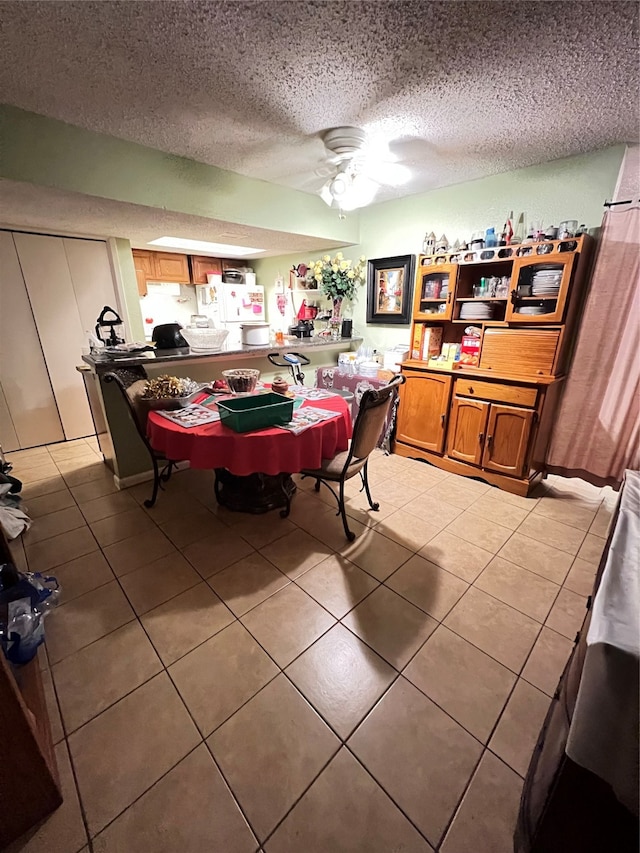 tiled dining area featuring ceiling fan and a textured ceiling