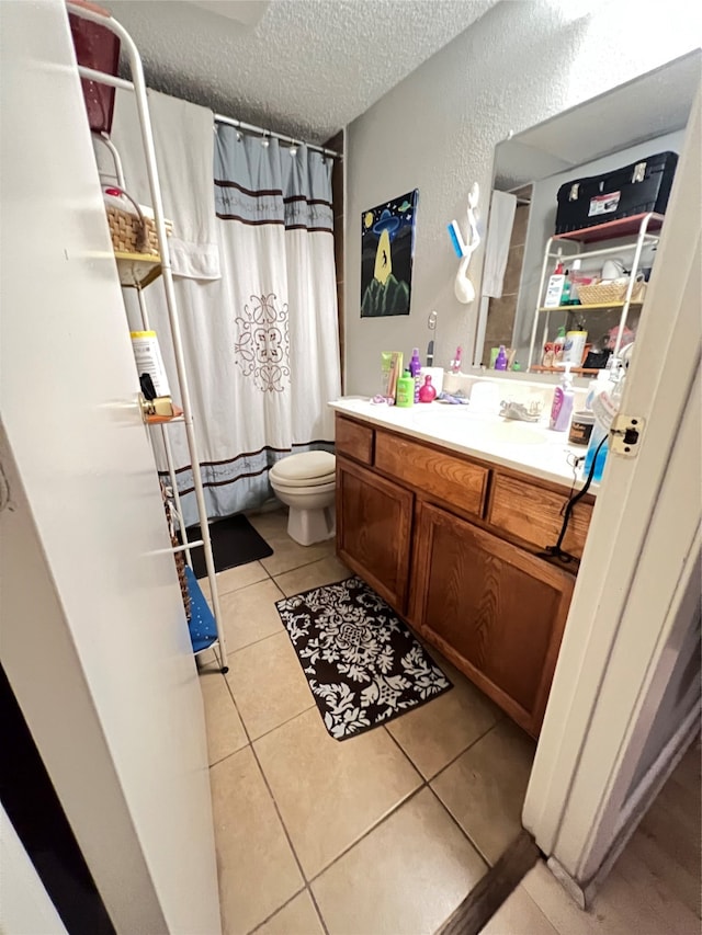 bathroom featuring tile flooring, vanity, toilet, and a textured ceiling