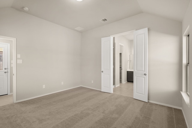 unfurnished bedroom with vaulted ceiling and light carpet