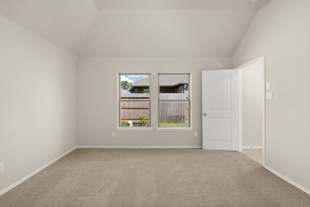 carpeted empty room featuring lofted ceiling