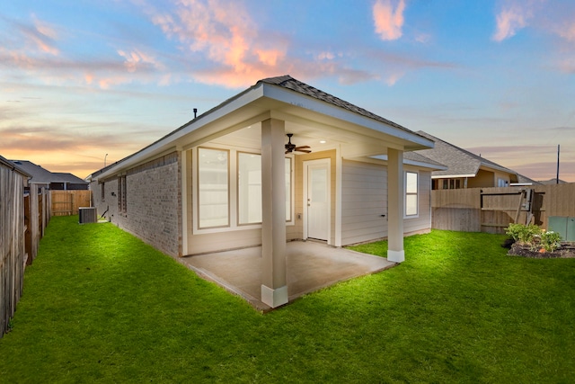 back house at dusk with ceiling fan, a lawn, a patio, and central AC unit