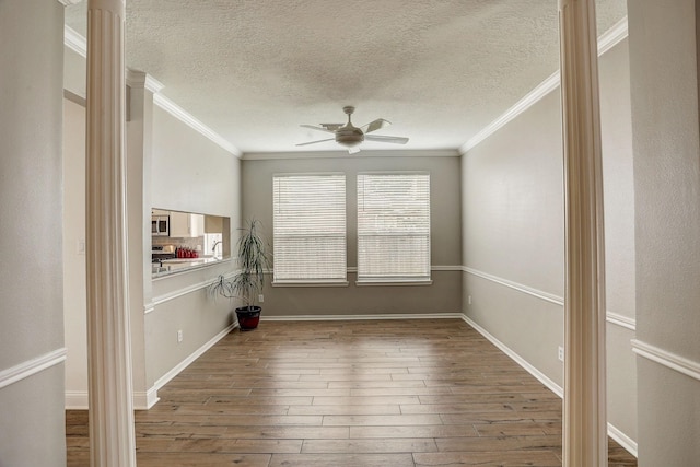 spare room featuring a ceiling fan, a textured ceiling, wood finished floors, and ornamental molding