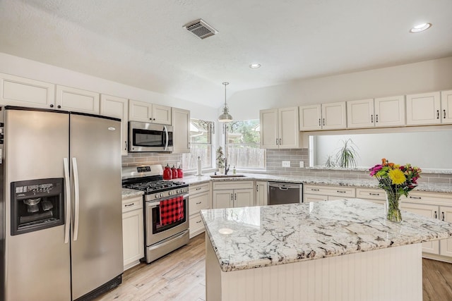 kitchen featuring visible vents, pendant lighting, tasteful backsplash, light wood-style floors, and appliances with stainless steel finishes