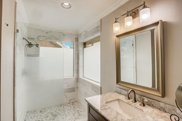 bathroom with vanity, crown molding, a textured ceiling, and walk in shower