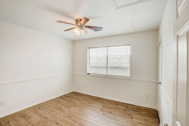 spare room featuring baseboards, attic access, a textured ceiling, a ceiling fan, and wood-type flooring