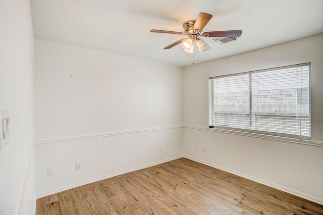 unfurnished room featuring baseboards, wood-type flooring, visible vents, and a ceiling fan