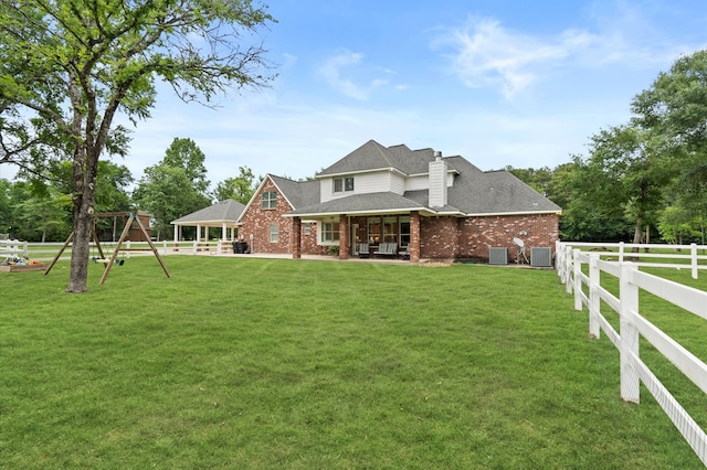 view of front of home with a playground, central AC unit, and a front lawn