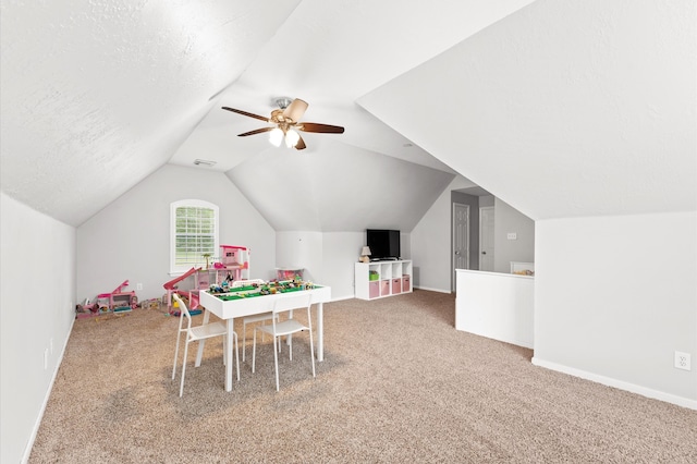 recreation room with carpet flooring, a textured ceiling, vaulted ceiling, and ceiling fan