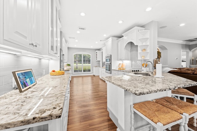 kitchen featuring white cabinets, a kitchen breakfast bar, and light stone countertops