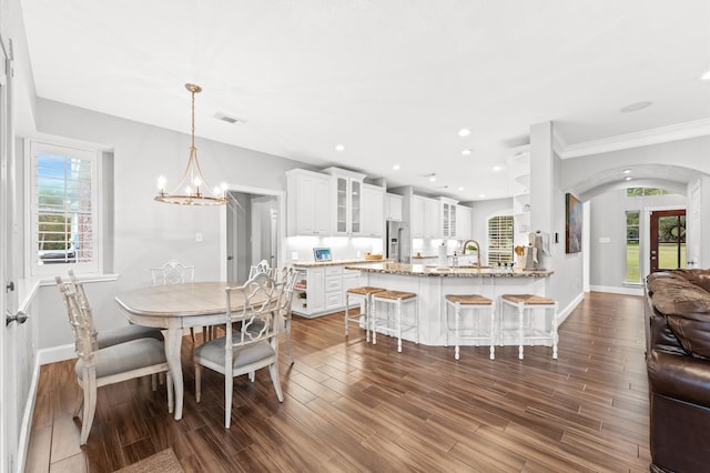 dining area featuring hardwood / wood-style floors, sink, a healthy amount of sunlight, and a notable chandelier