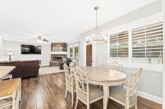 dining area featuring a wealth of natural light, a fireplace, dark wood-type flooring, and ceiling fan with notable chandelier