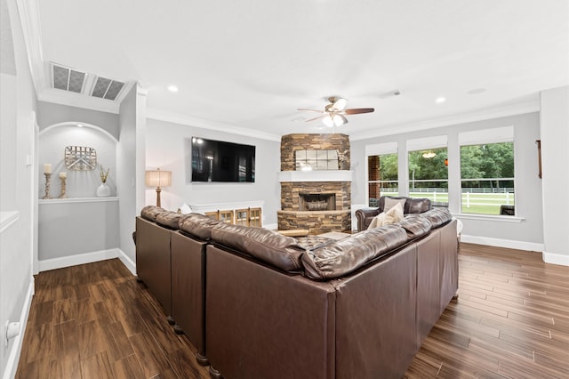 living room with a stone fireplace, ceiling fan, and ornamental molding