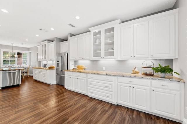 kitchen with white cabinets, hanging light fixtures, dark hardwood / wood-style floors, light stone counters, and stainless steel appliances