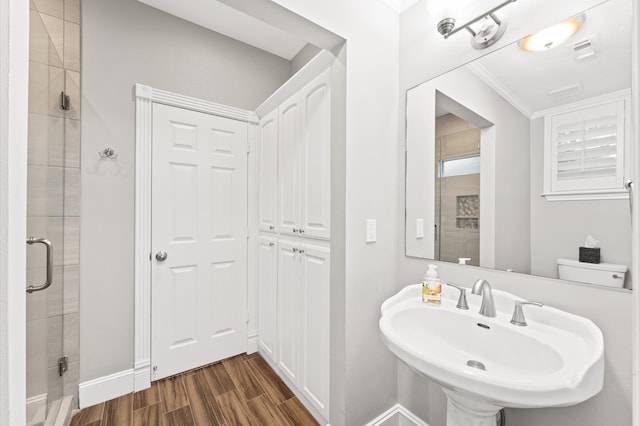 bathroom featuring toilet, a shower with door, crown molding, and sink