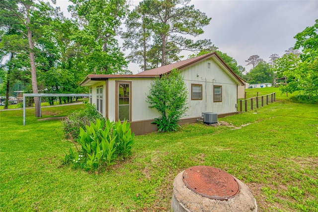 view of side of property with central air condition unit and a lawn