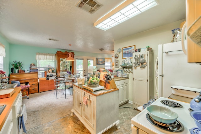 kitchen featuring white refrigerator, french doors, a kitchen island, a textured ceiling, and light tile patterned floors