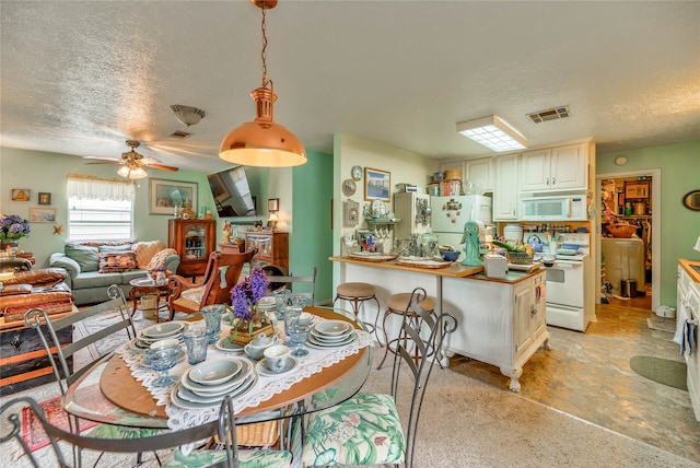 tiled dining room with a textured ceiling and ceiling fan