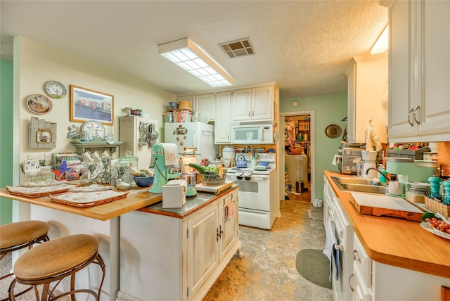 kitchen featuring light tile patterned flooring, white appliances, sink, butcher block countertops, and a textured ceiling