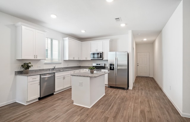 kitchen featuring hardwood / wood-style floors, a kitchen island, white cabinetry, and appliances with stainless steel finishes