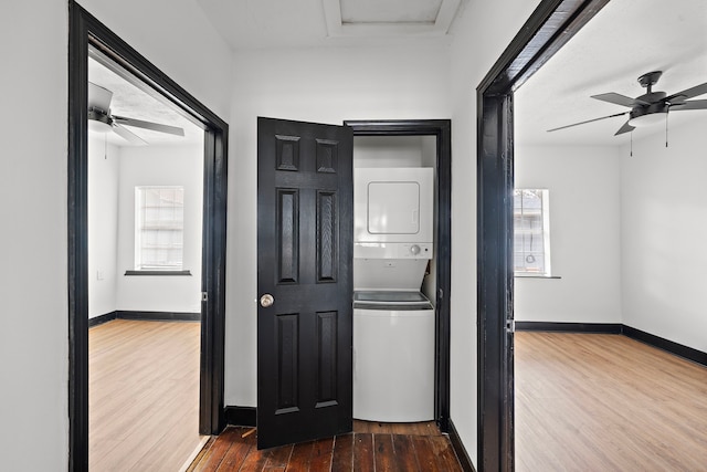 hallway with stacked washing maching and dryer and hardwood / wood-style flooring