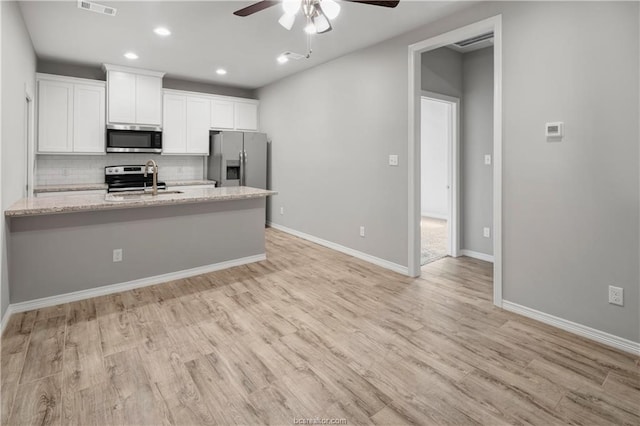 kitchen with ceiling fan, light hardwood / wood-style flooring, backsplash, white cabinets, and appliances with stainless steel finishes