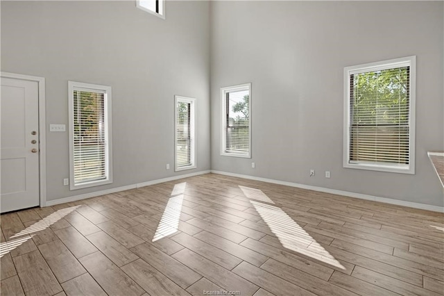 interior space featuring a healthy amount of sunlight, light wood-type flooring, and a high ceiling