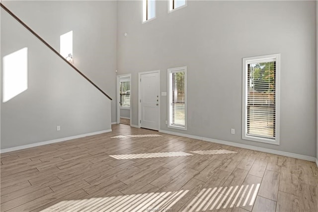 entryway with plenty of natural light, a towering ceiling, and light hardwood / wood-style flooring