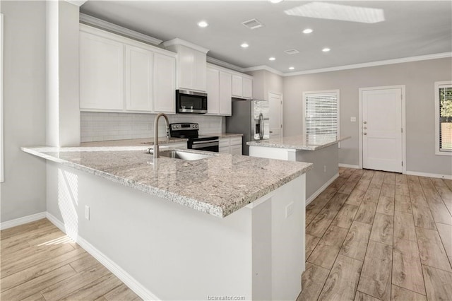 kitchen with backsplash, ornamental molding, light wood-type flooring, appliances with stainless steel finishes, and sink