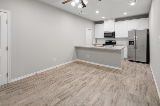 kitchen with appliances with stainless steel finishes, white cabinetry, ceiling fan, and light hardwood / wood-style flooring