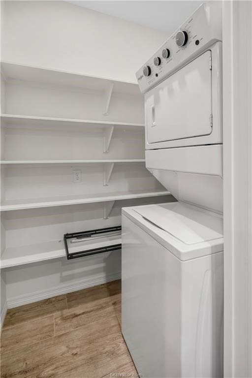 clothes washing area with light hardwood / wood-style flooring and stacked washer / dryer