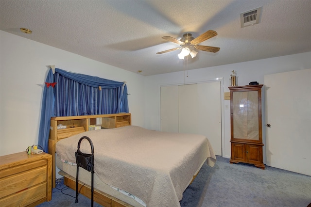 carpeted bedroom with ceiling fan, a closet, and a textured ceiling