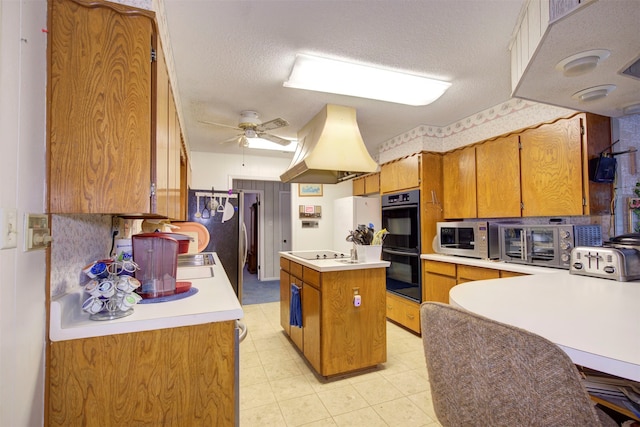 kitchen with a kitchen island, ceiling fan, light tile floors, black appliances, and a textured ceiling