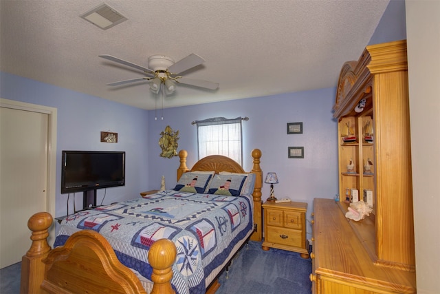 bedroom featuring a textured ceiling, ceiling fan, and dark carpet