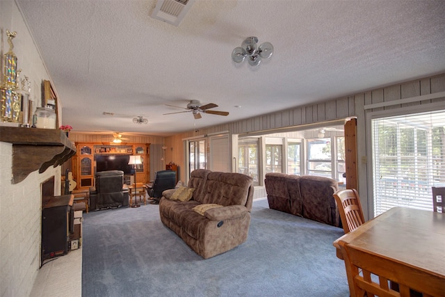 living room featuring a textured ceiling, wooden walls, ceiling fan, and carpet floors