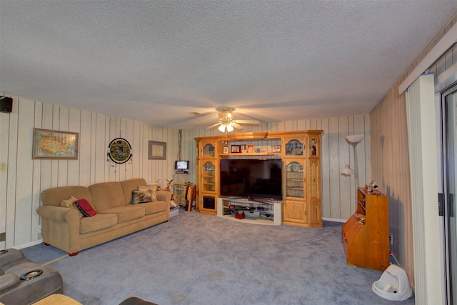 living room featuring carpet floors, a textured ceiling, wooden walls, and ceiling fan