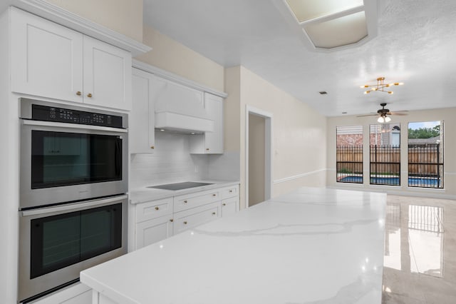17402 Wilton Park Ct, Spring, TX 77379 - kitchen featuring white cabinetry, stainless steel double oven, ceiling fan, and tasteful backsplash
