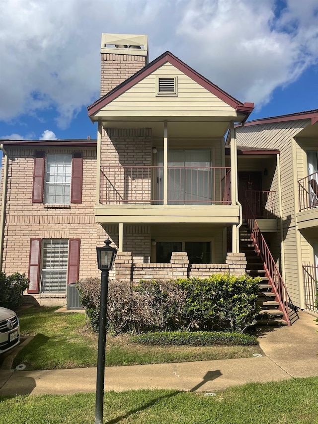 view of front of house with a balcony and a front lawn